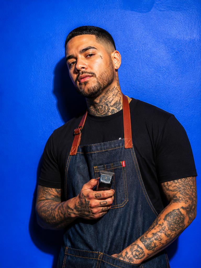 Barber with clippers against a cobalt blue wall